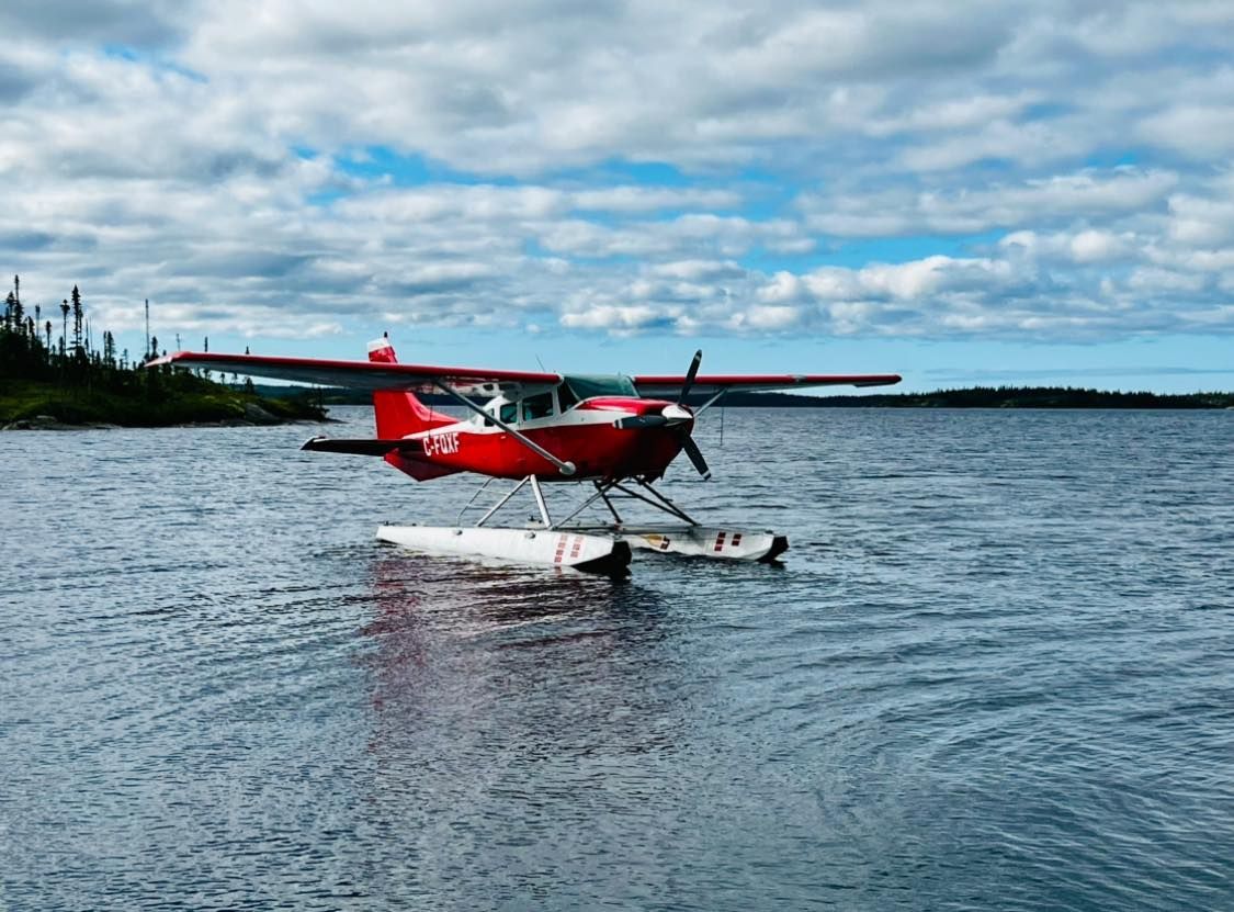 Un hydravion rouge est assis sur des flotteurs au milieu d'un lac.