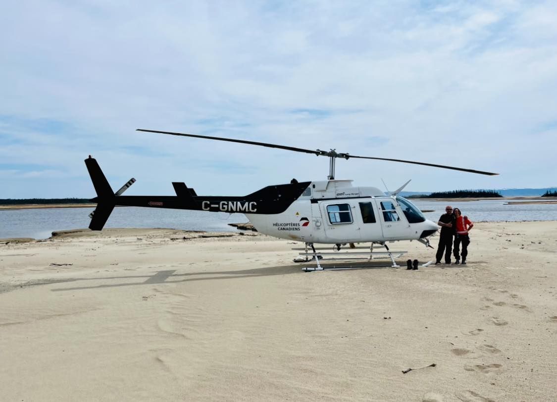 Un hélicoptère est stationné sur la plage avec les lettres c-bnmc sur le côté