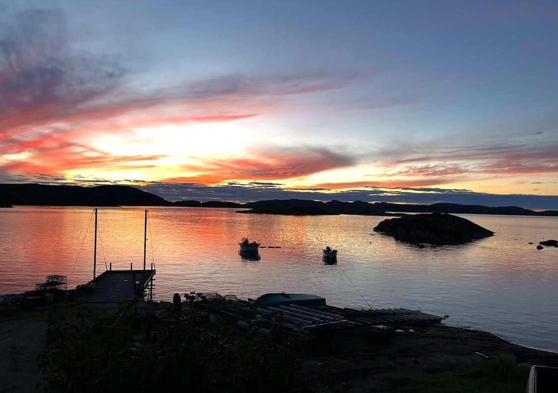 Un coucher de soleil sur un plan d'eau avec un quai au premier plan.