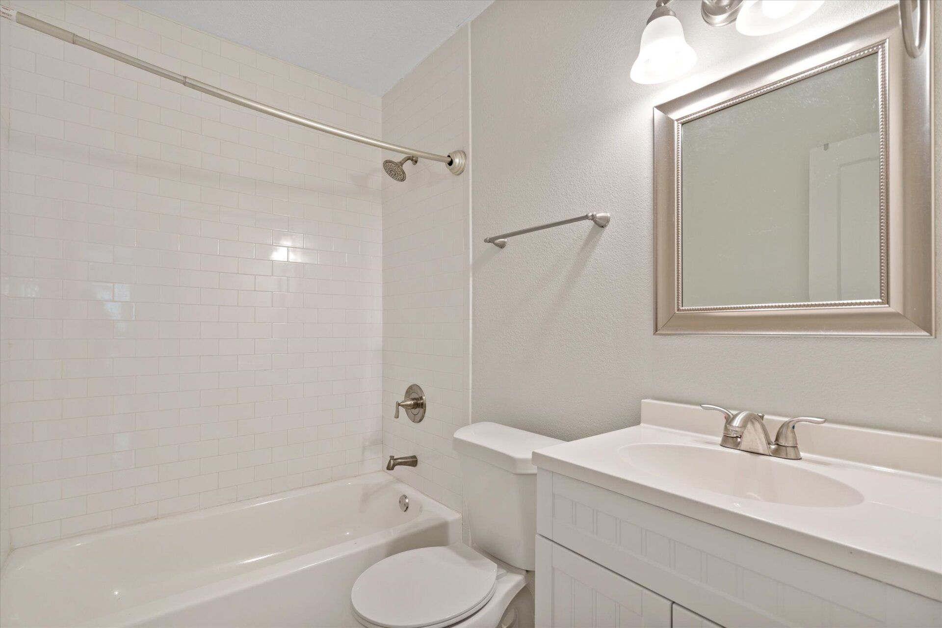 A bathroom with a toilet , sink , bathtub and mirror.