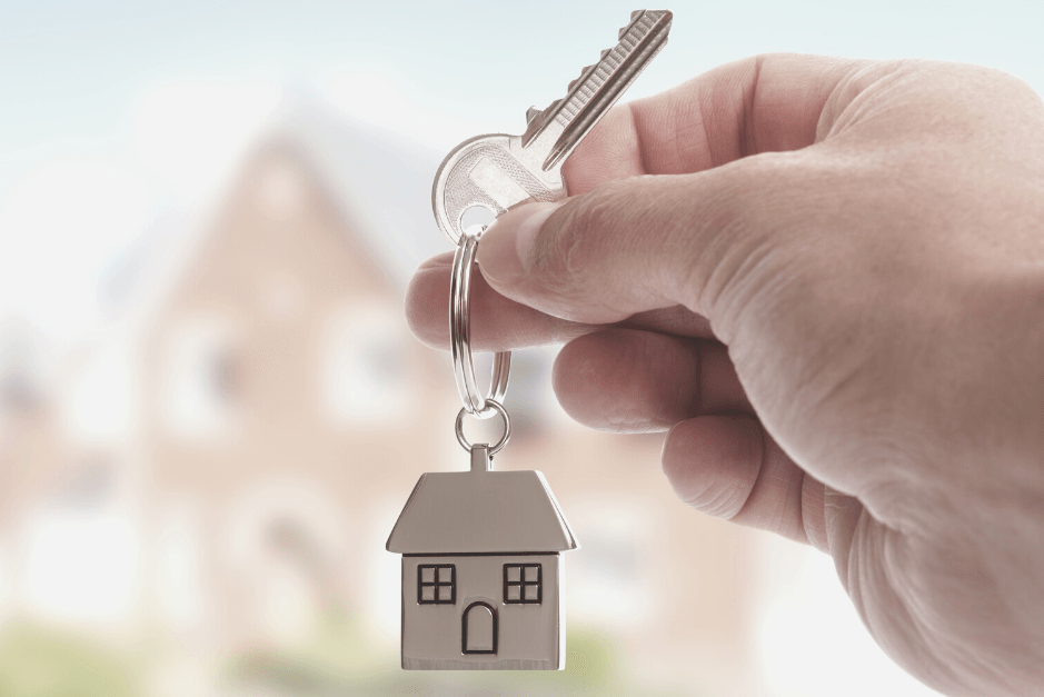 hand holding a key with house keychain