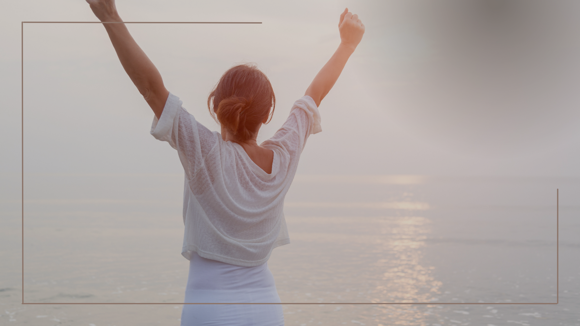 Person facing the sea with arms raised, representing letting go and moving forward from the past. 