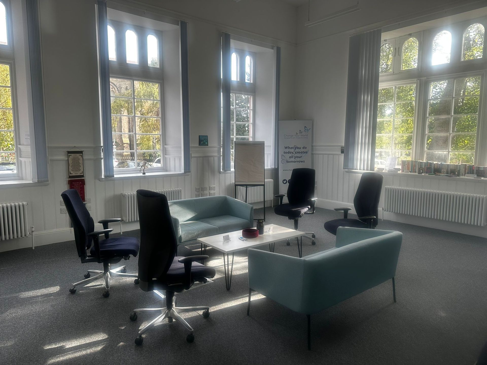 Meeting room with blue sofas, black office chairs, whiteboard, and large windows.