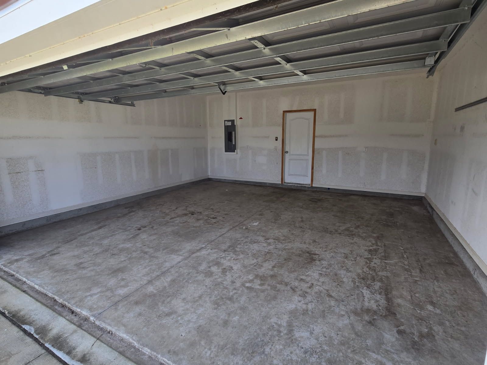 Empty unfinished garage interior with exposed ceiling beams and bare concrete floor