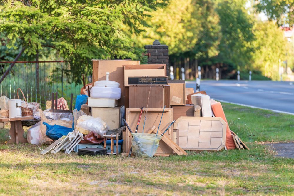 A pile of junk is sitting on the grass next to a road.
