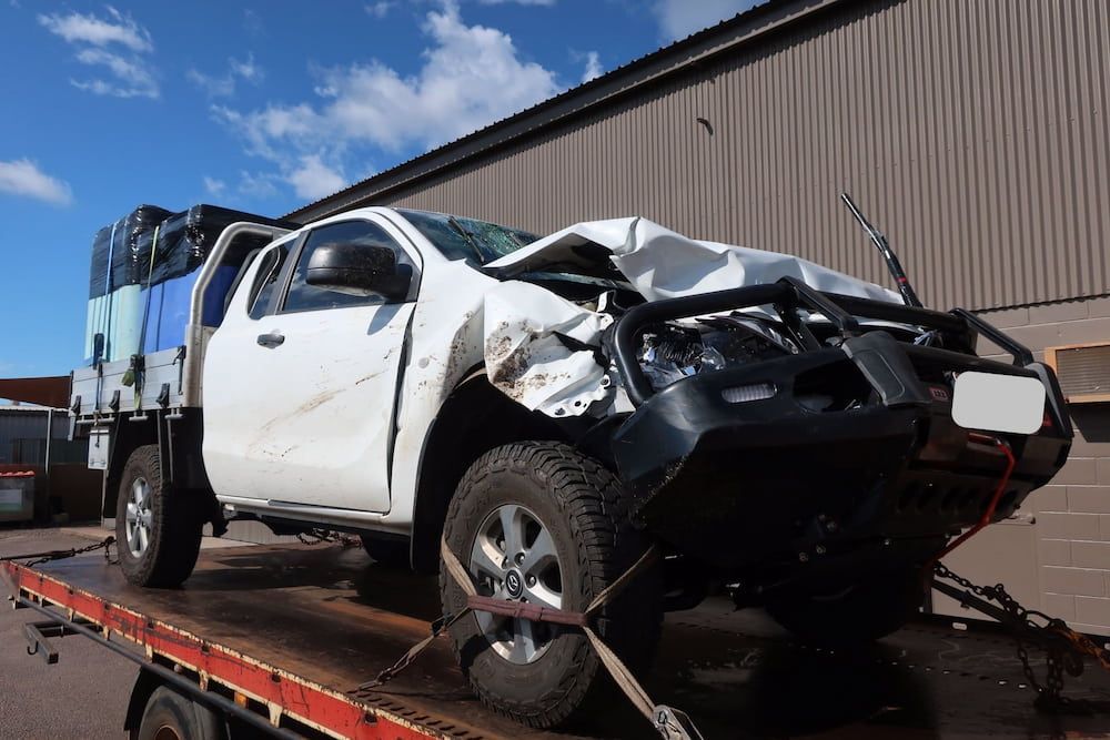 A Wrecked Truck is Sitting on Top of a Tow Truck — Al's Panel Shop in Berrimah, NT