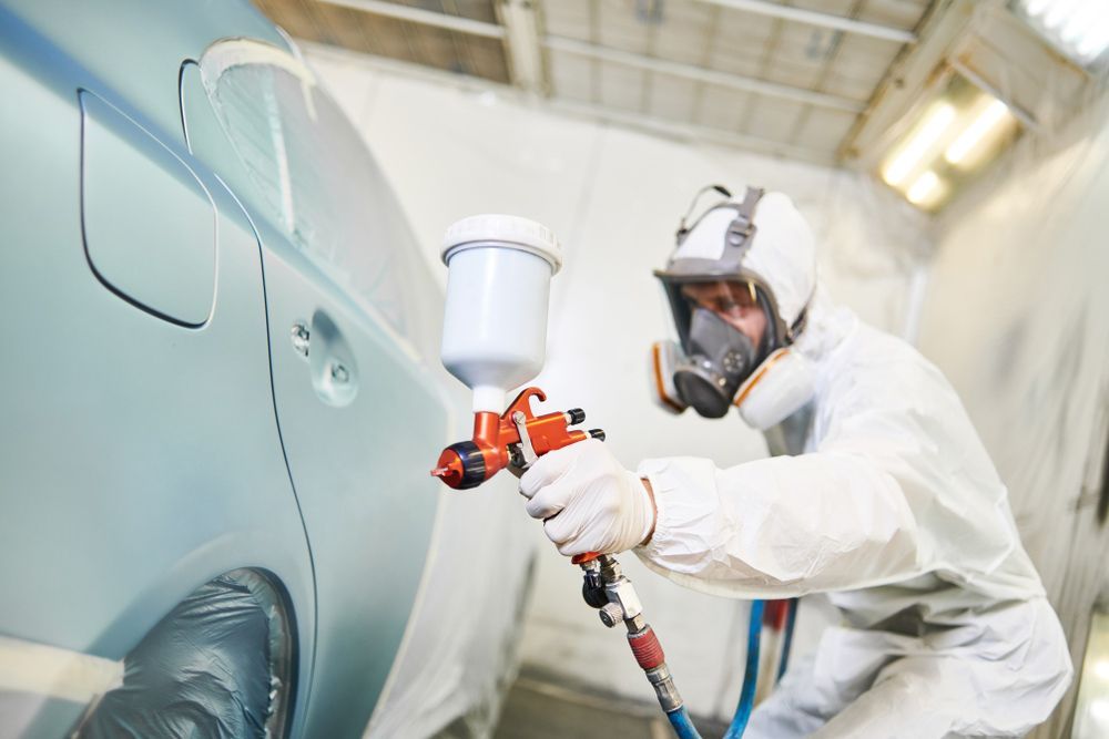 Man Spray Painting Car as Part of Panel Beating Process