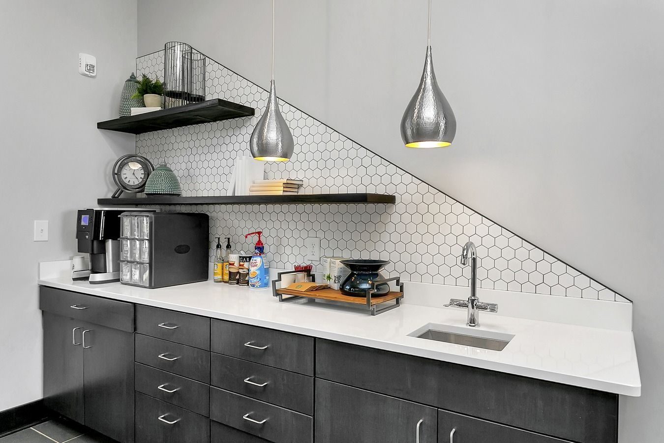 Modern kitchen counter with black cabinets, white countertop, open shelves, and two pendant lights at Haven on Tucker Apartments in Louisville, KY