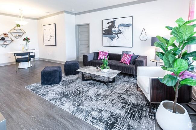 Modern living room with gray sofa, shag rug, coffee table, and large potted plant at Haven on Tucker Apartments in Louisville, KY.