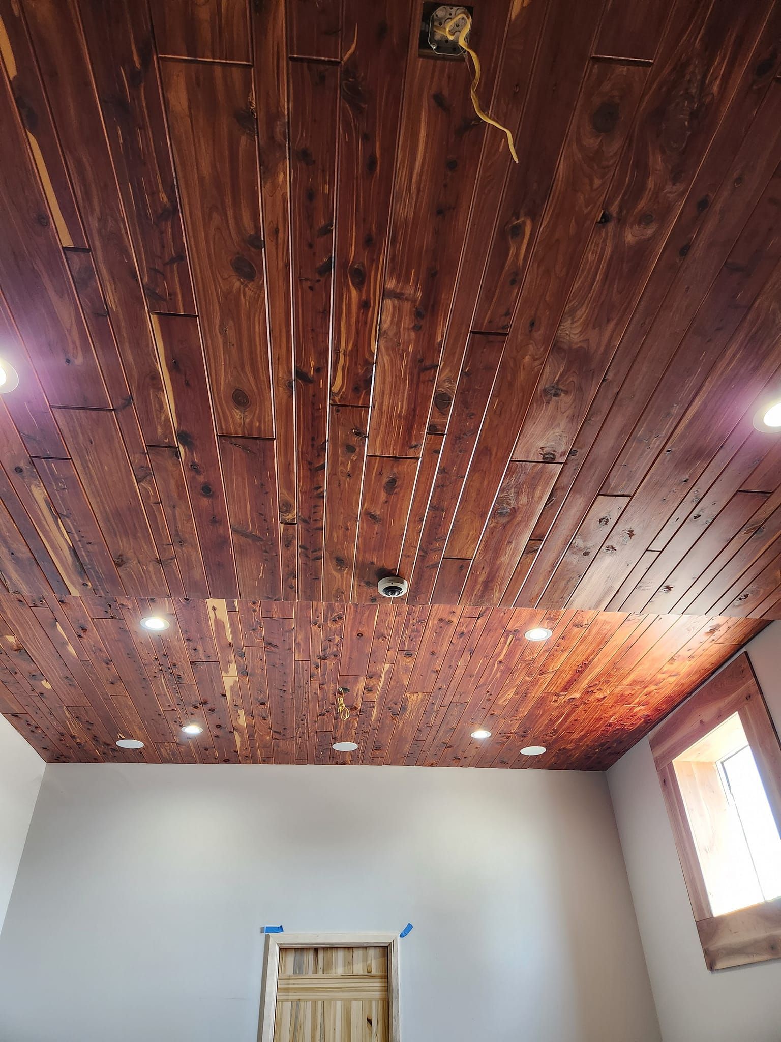 A room with a wooden ceiling and a door.