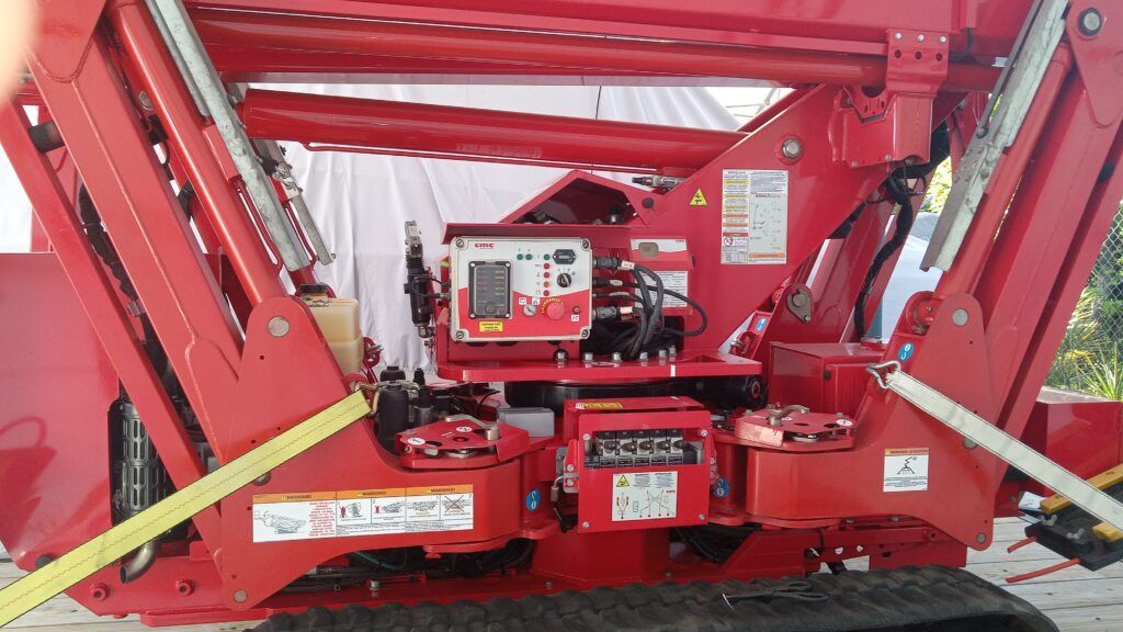 Red machinery under a canopy, with hydraulic arms and a central control panel.