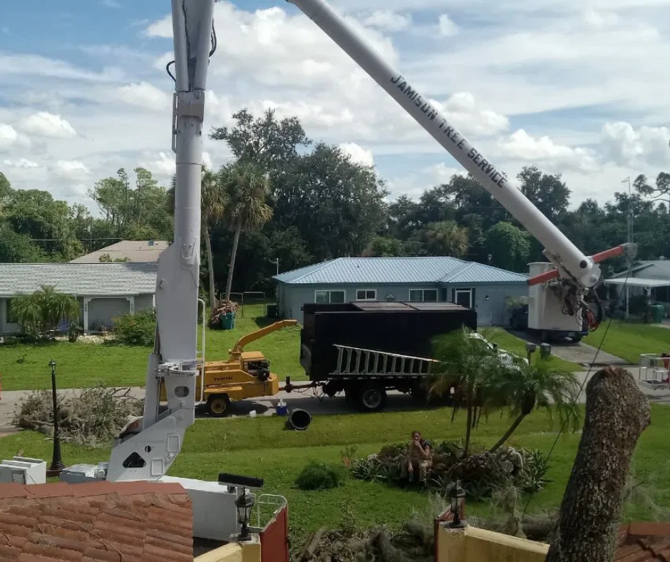 Utility truck and yellow crane working on a residential street under a cloudy sky