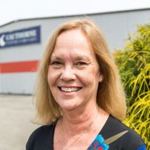 A woman is smiling in front of a building.
