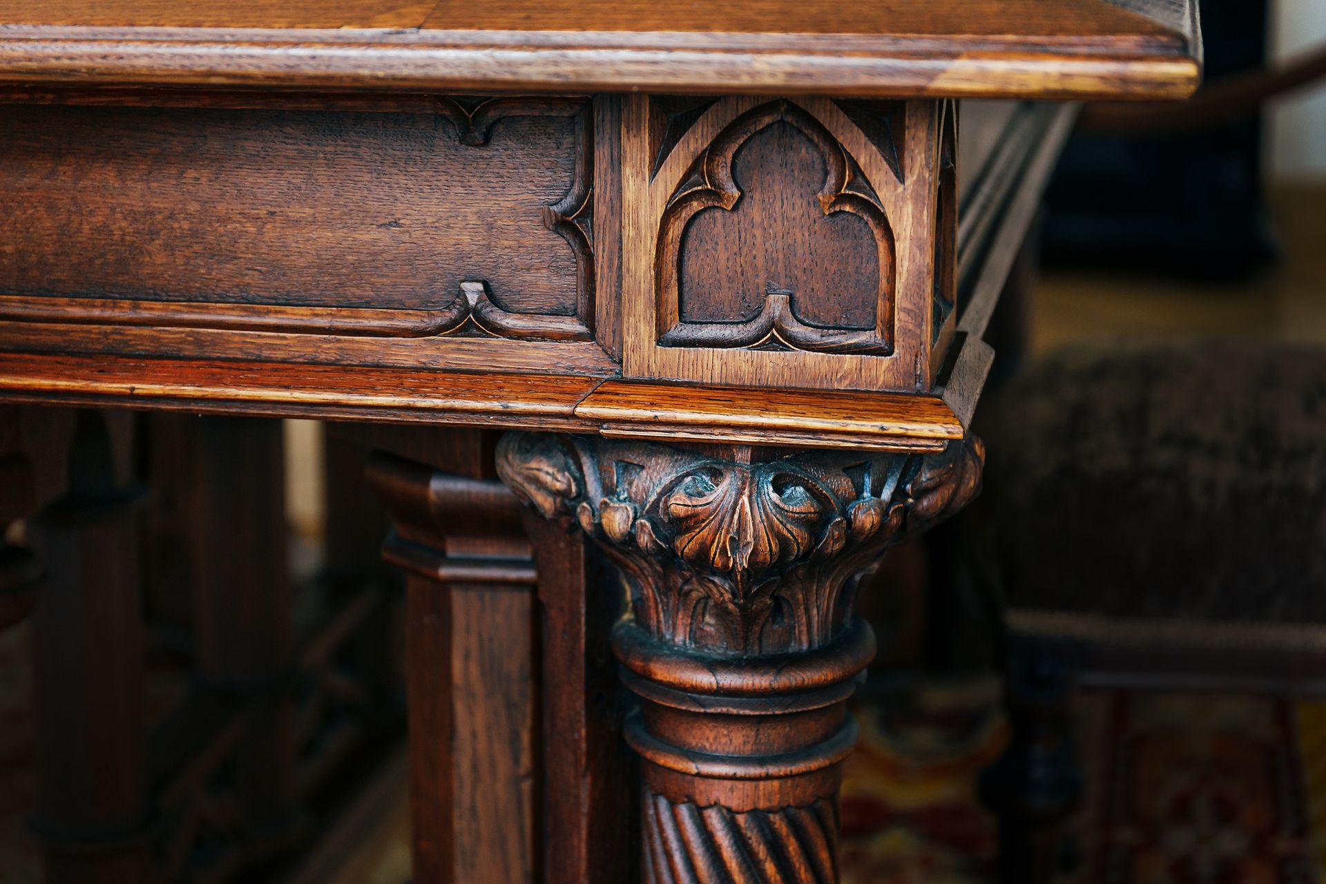 Ornate carved wooden table leg and apron with dark finish and floral details