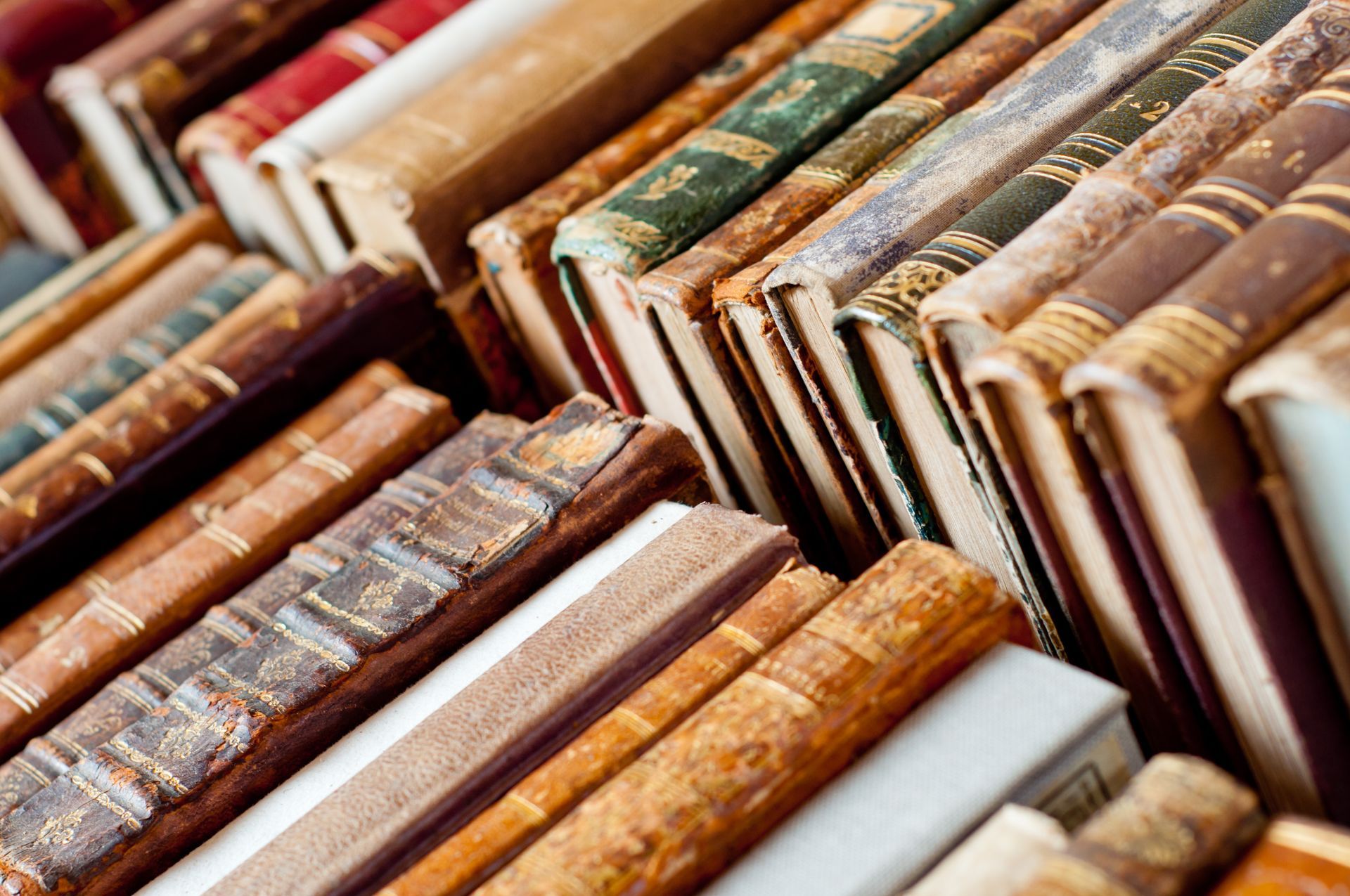 Rows of old, worn books with colorful spines stacked tightly on a shelf