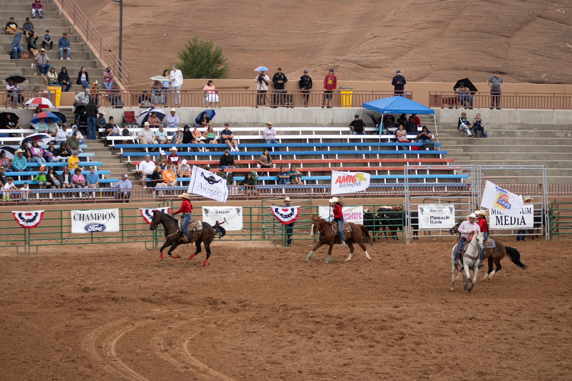 A group of people riding horses in a rodeo arena