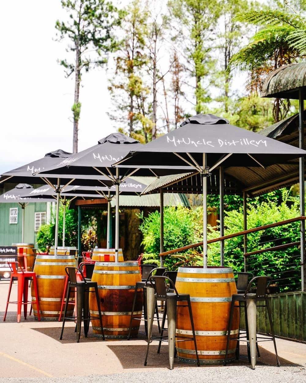 A Row of Tables and Chairs Under Umbrellas With Barrels in the Background — Meraki Equestrian Centre in Mareeba, QLD