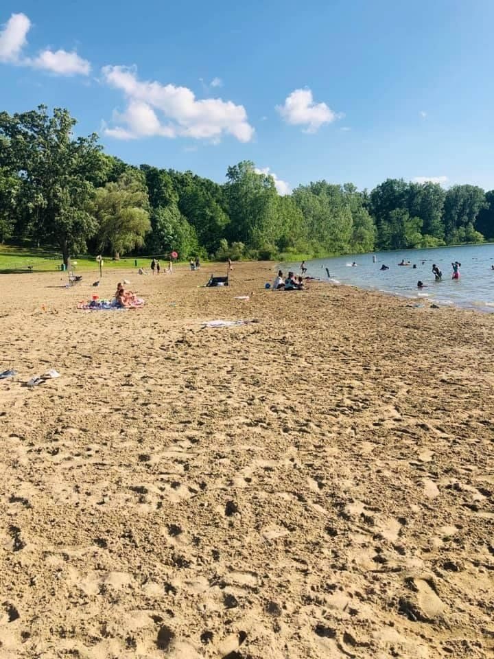 A beach with a lot of people on it and a lake in the background.