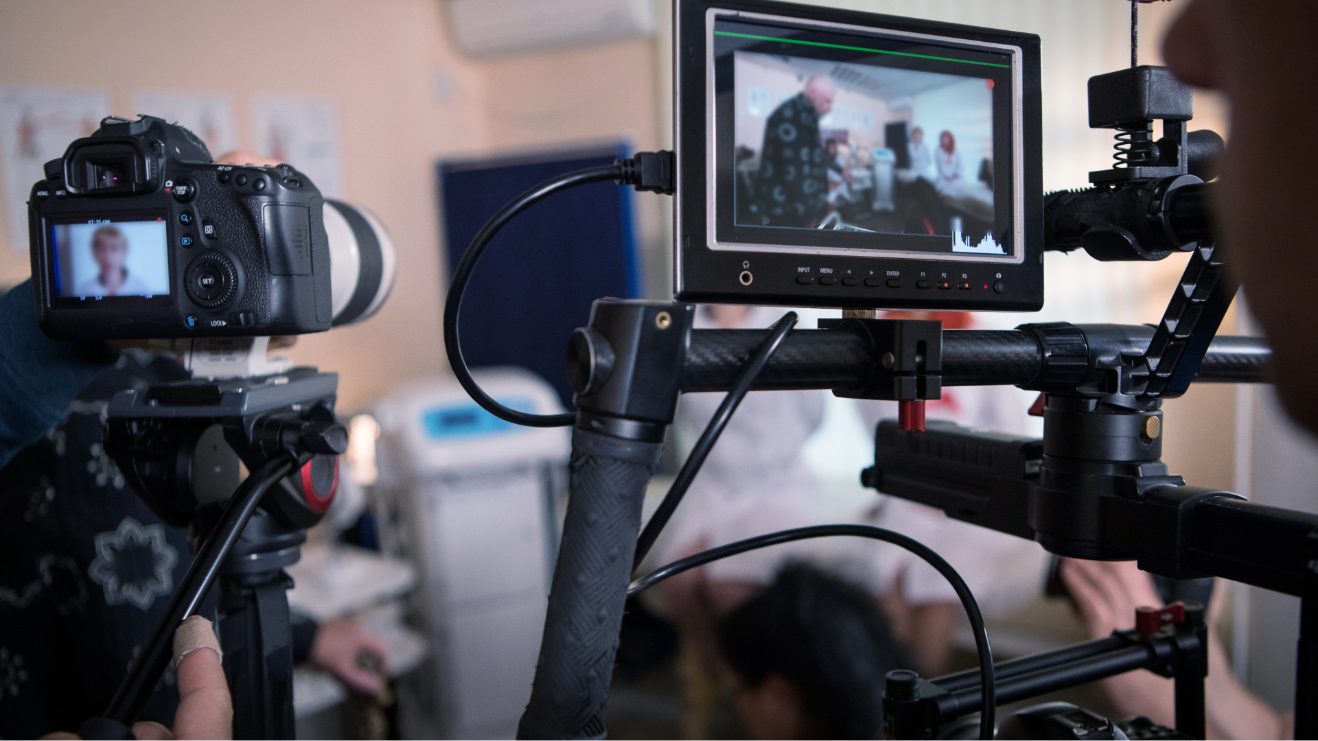 Two cameras filming a scene indoors, with one monitor showing a person in a coat outdoors.