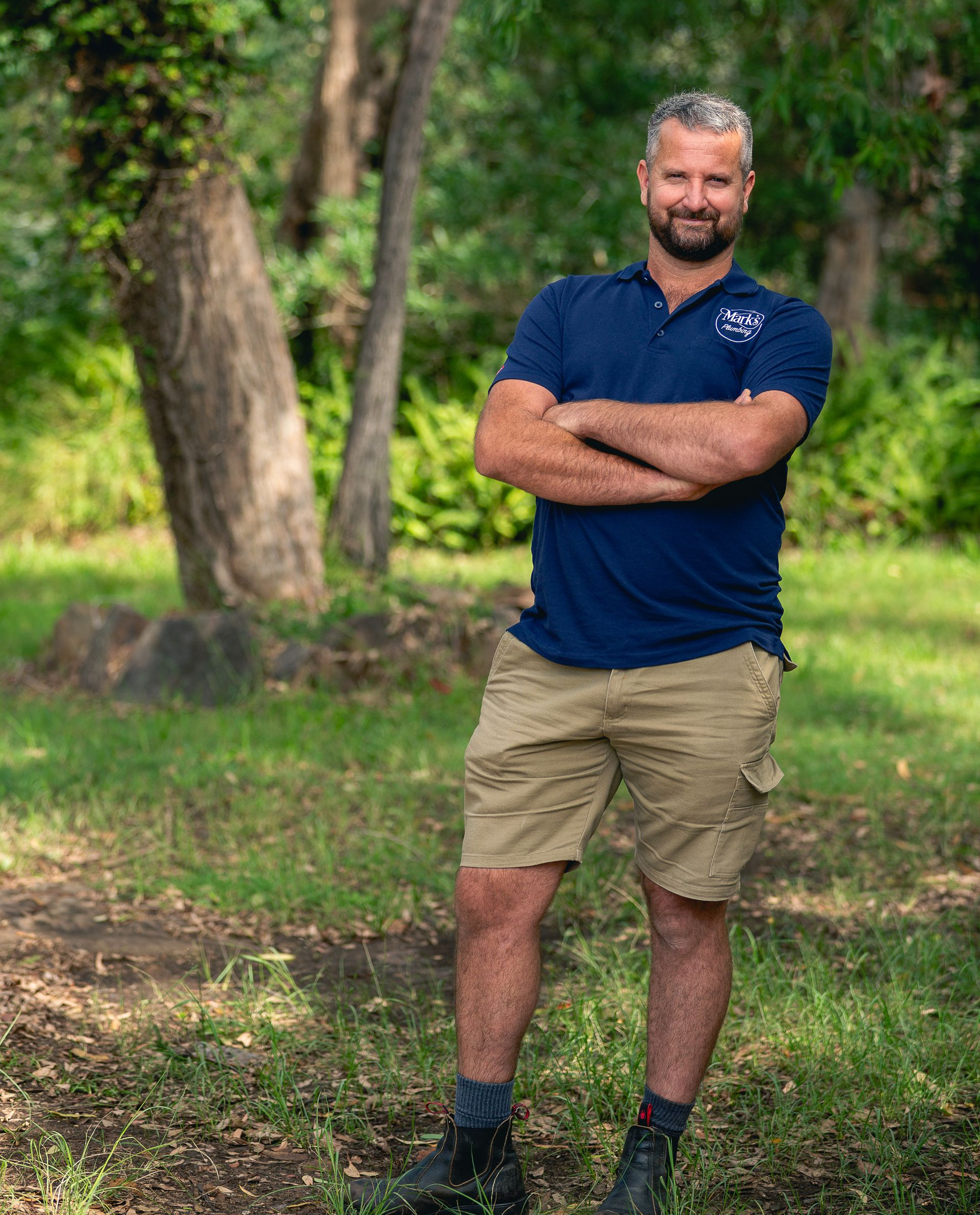 Man Standing Outdoors With Arms Crossed, Wearing a Navy Shirt, Khaki Shorts — Mark's Plumbing in Budgewoi, NSW