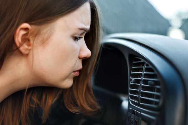 Woman looking into a car dashboard vent, close-up side view in a dimly lit vehicle interior | Dub's Garage