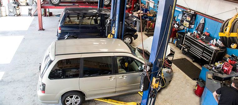 Silver SUV in an auto repair shop on a lift, with mechanics and tools visible in the background | Dub's Garage