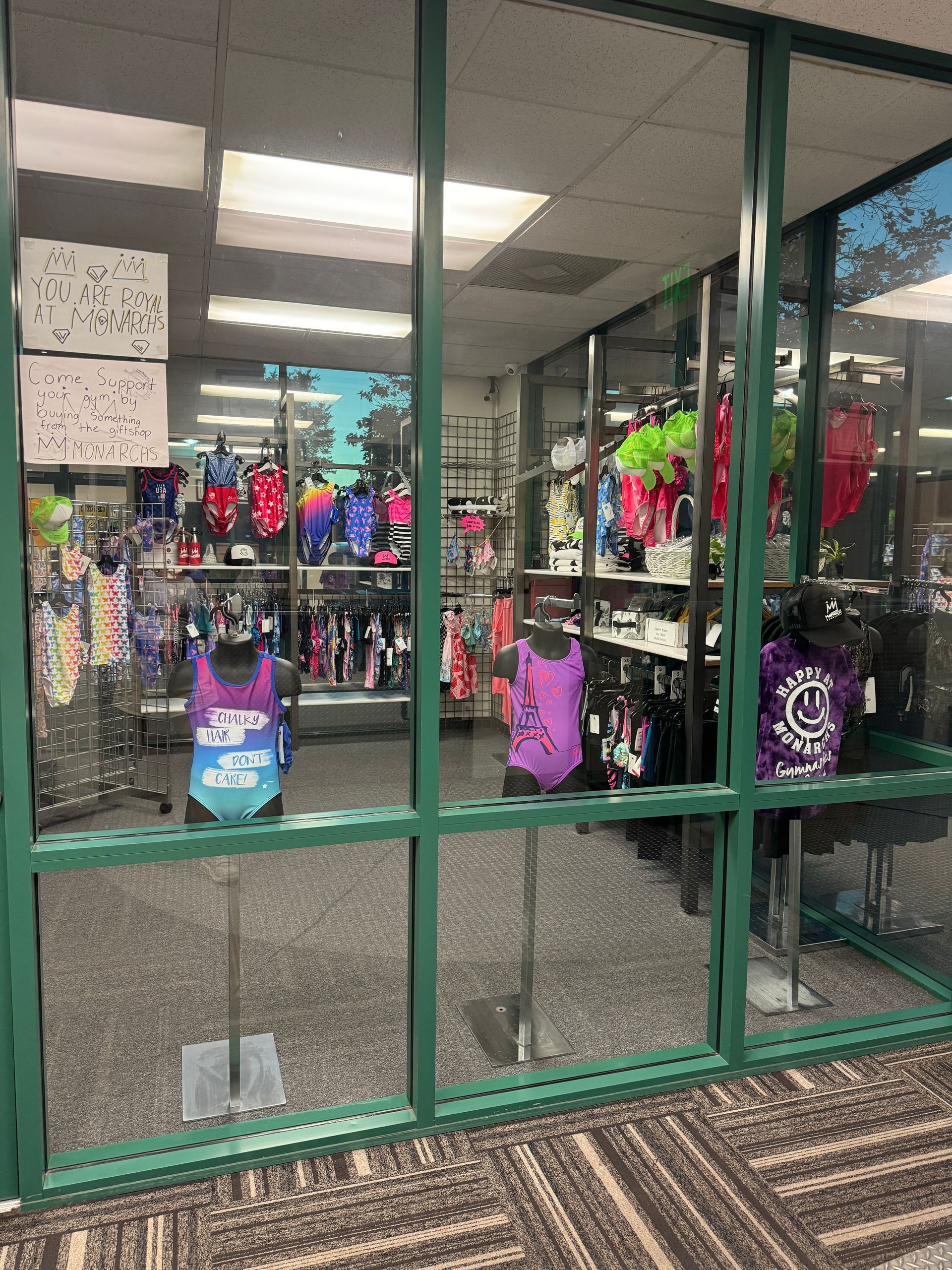 Storefront display with mannequins wearing colorful leotards and athletic wear.