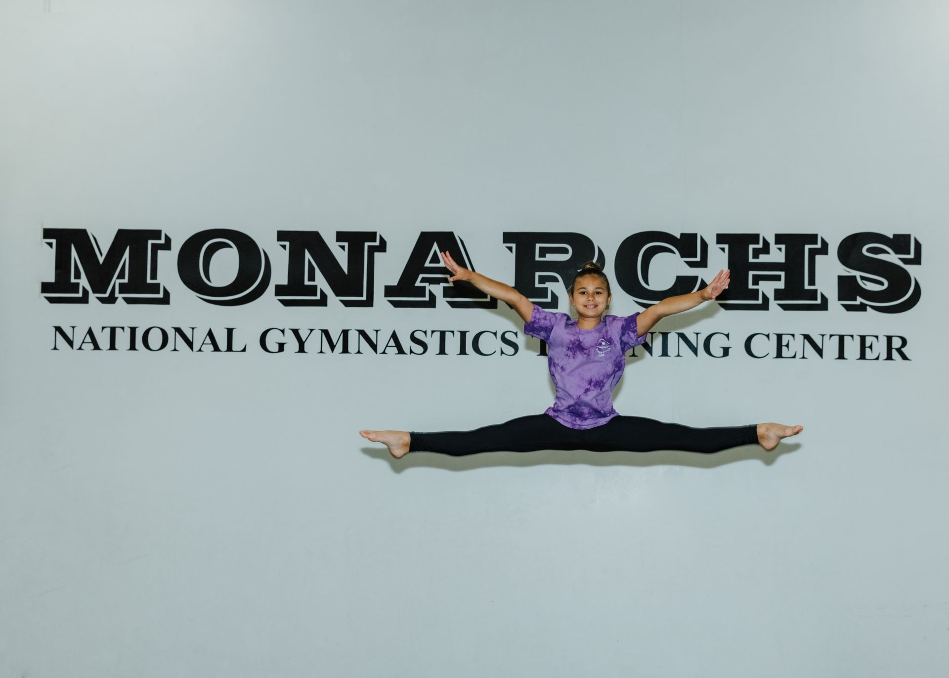 Gymnast in a split mid-air in front of a 