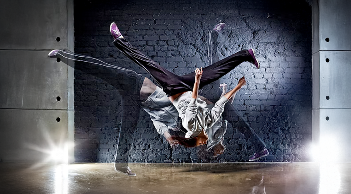 Dancer in mid-air performing a breakdancing move against a brick wall. Multiple exposure effect.