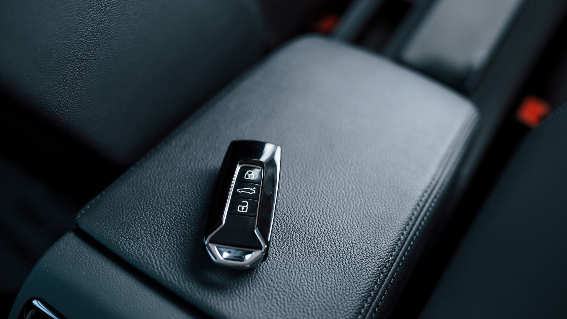 A car key is sitting on the arm rest of a car.