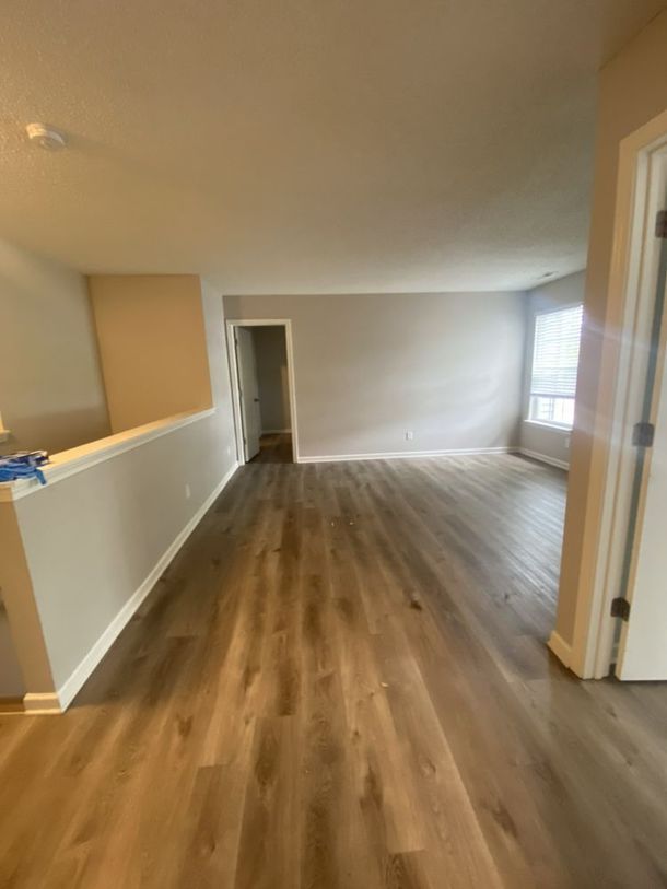 Empty living room with wood floors, beige walls, and a windowed doorway.