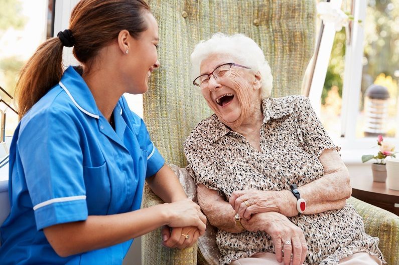 a nurse is talking to an elderly woman in a chair .
