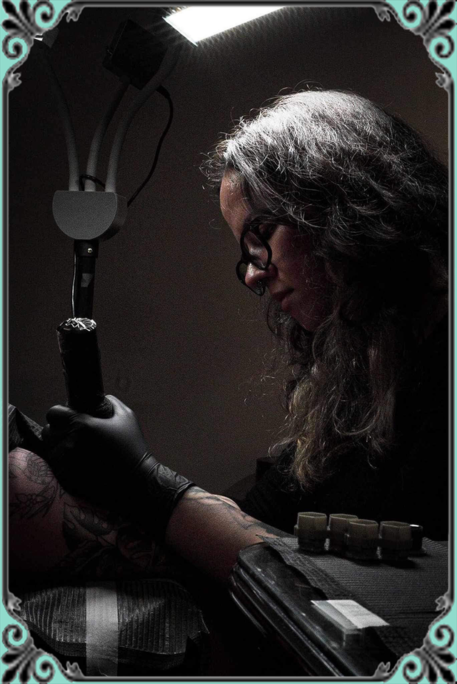 A woman is getting a tattoo on another person 's arm