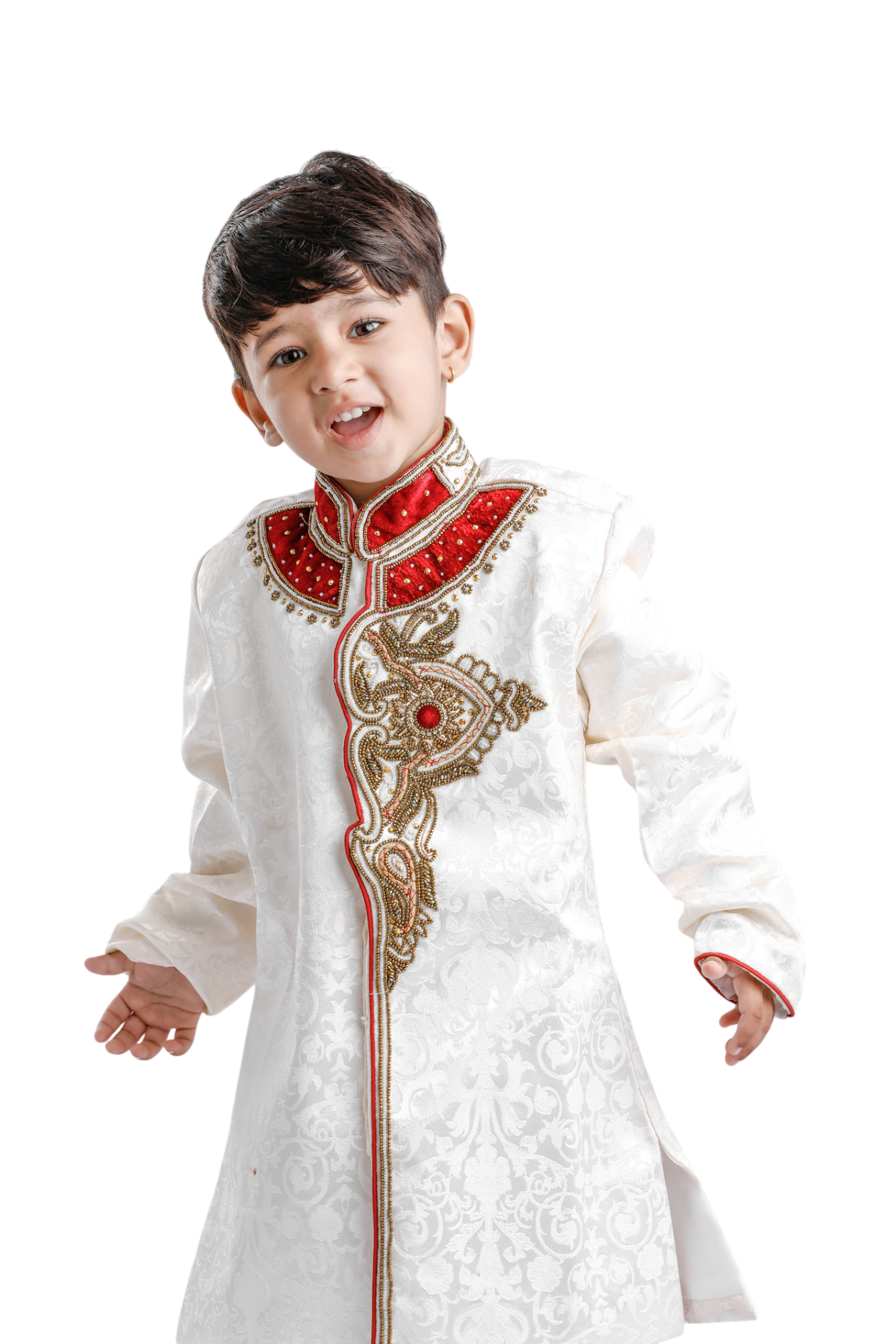 Young boy in traditional cream-colored Indian formal wear, smiling with open arms. Red and gold embroidery on the neckline and bodice. Young boy in traditional cream-colored Indian formal wear, smiling with open arms. Red and gold embroidery on the neckline and bodice.