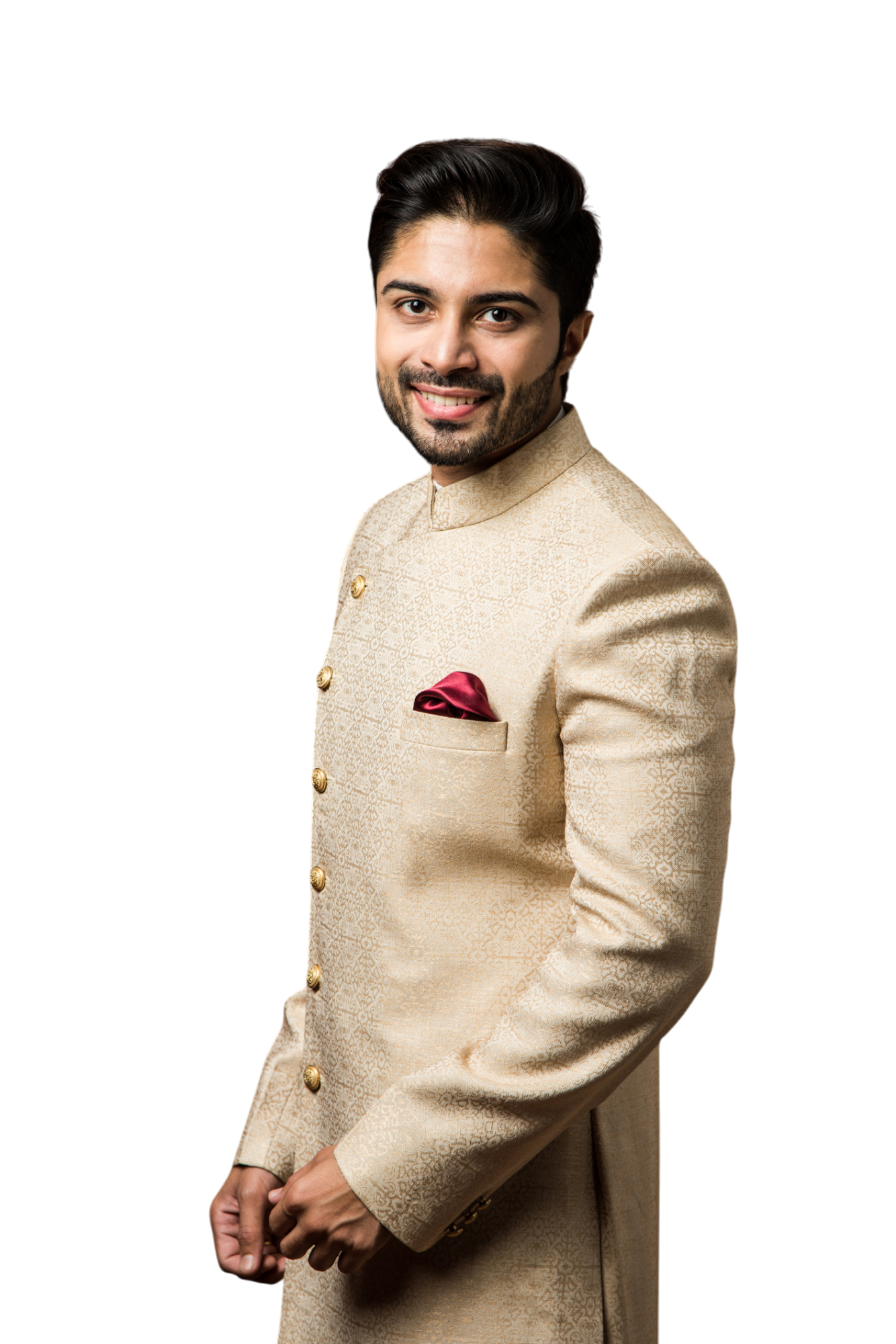 A smiling man in a beige embroidered sherwani, with a burgundy pocket square, stands against a white background. A smiling man in a beige embroidered sherwani, with a burgundy pocket square, stands against a white background.