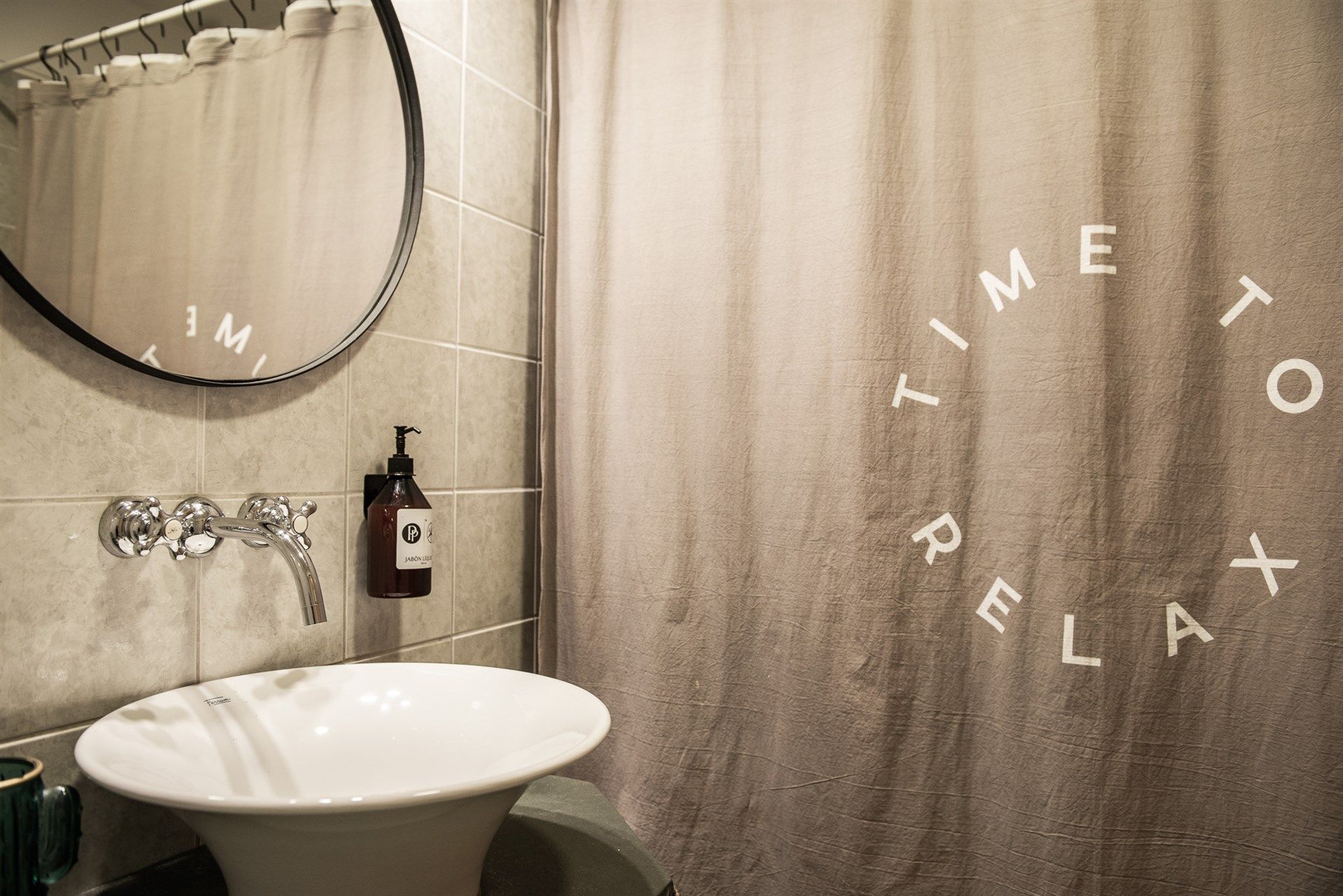 Un baño con lavabo, espejo y cortina de ducha que dice 