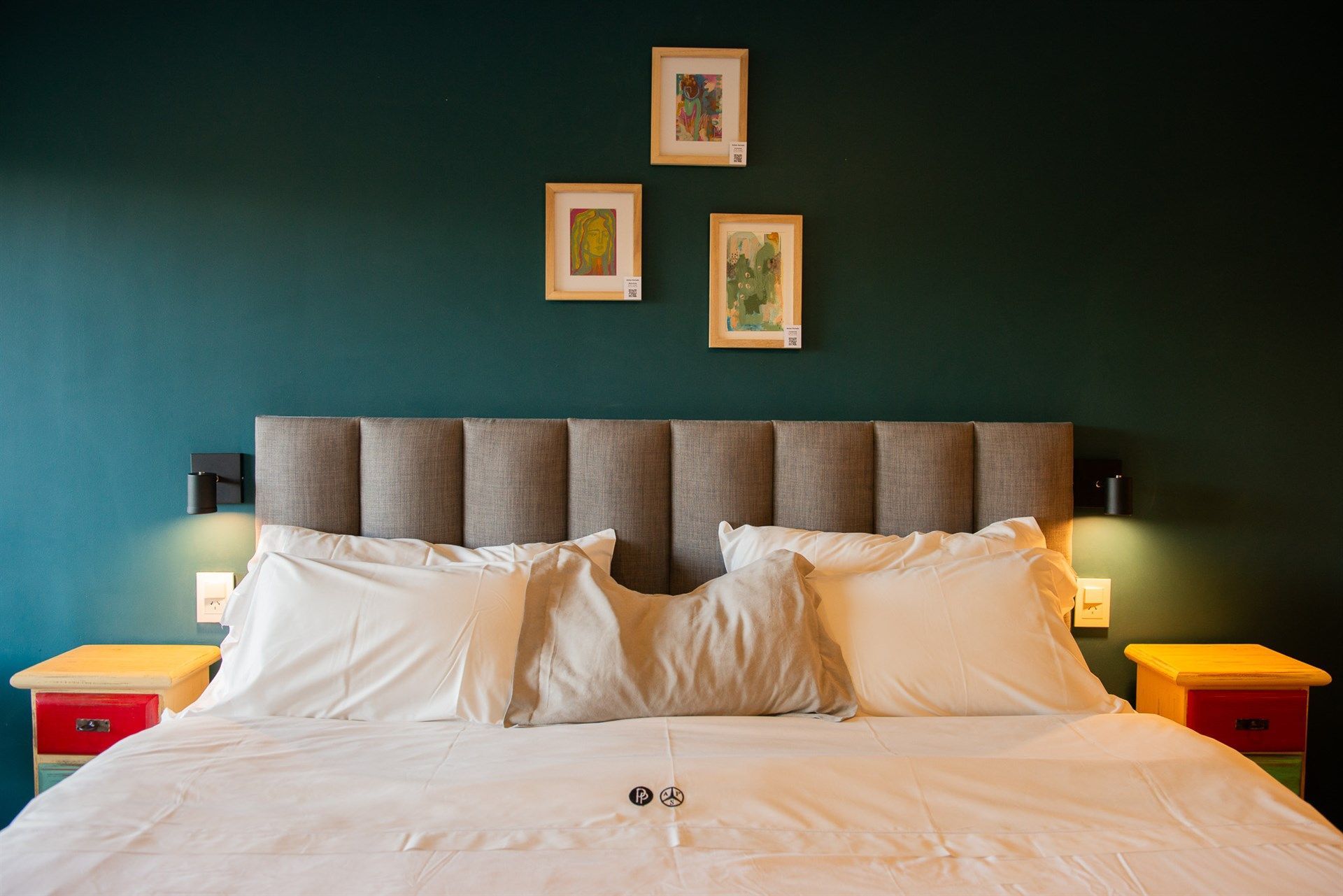 Una cama con sábanas blancas y almohadas en una habitación de hotel con una pared verde.