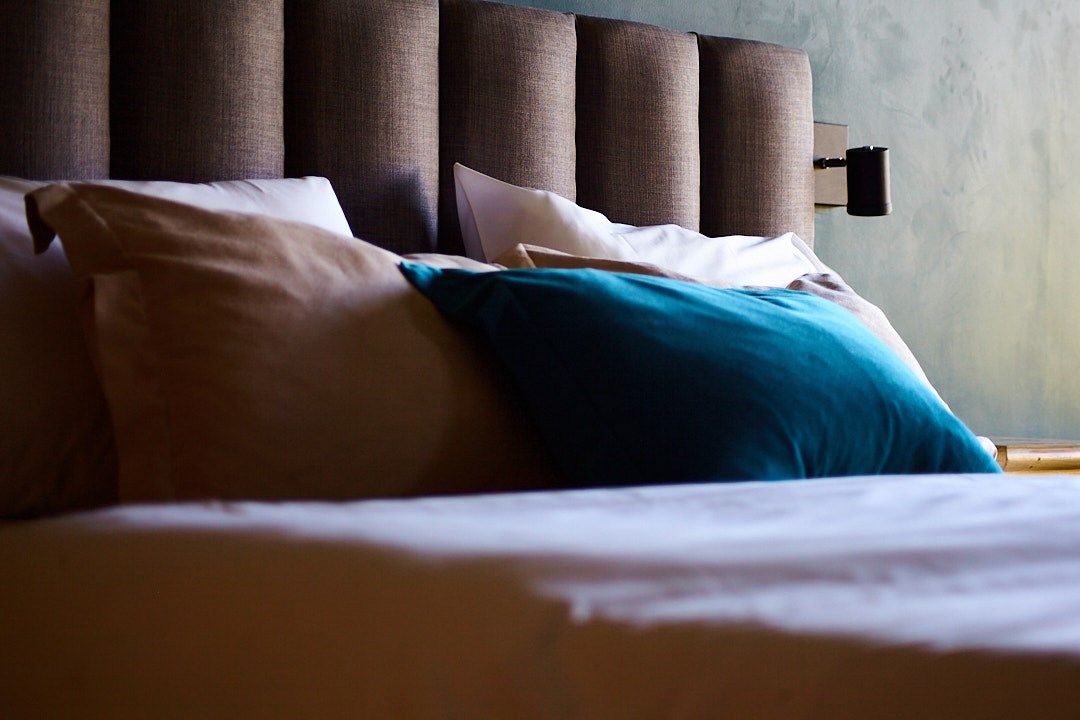 Una cama con un cabecero marrón y almohadas azules.