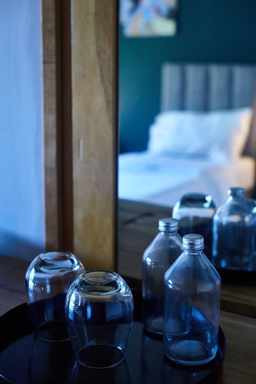 Una bandeja de vasos y botellas frente a un espejo en una habitación de hotel.