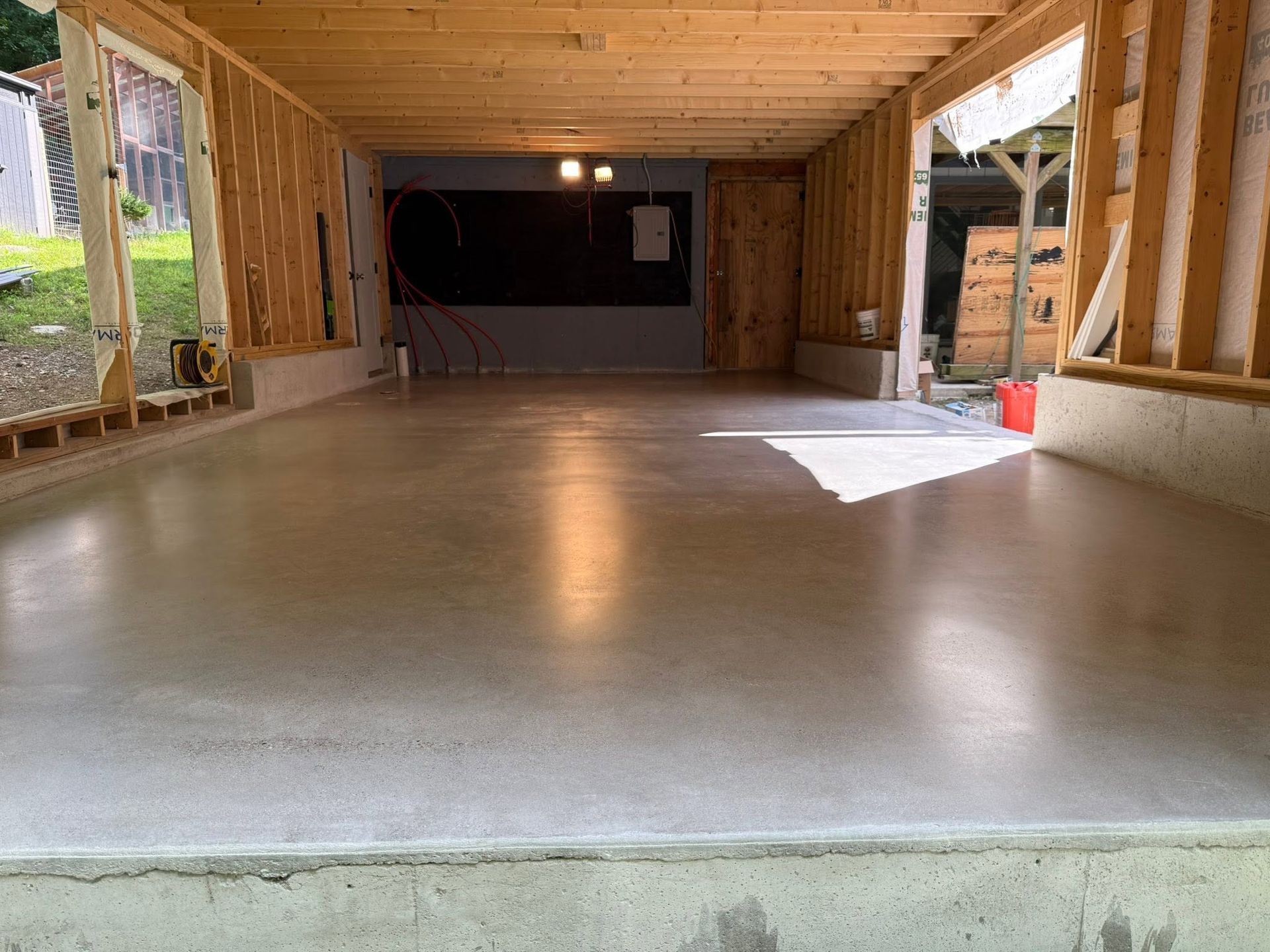 Empty newly built wooden room with unfinished concrete floor and open sides.