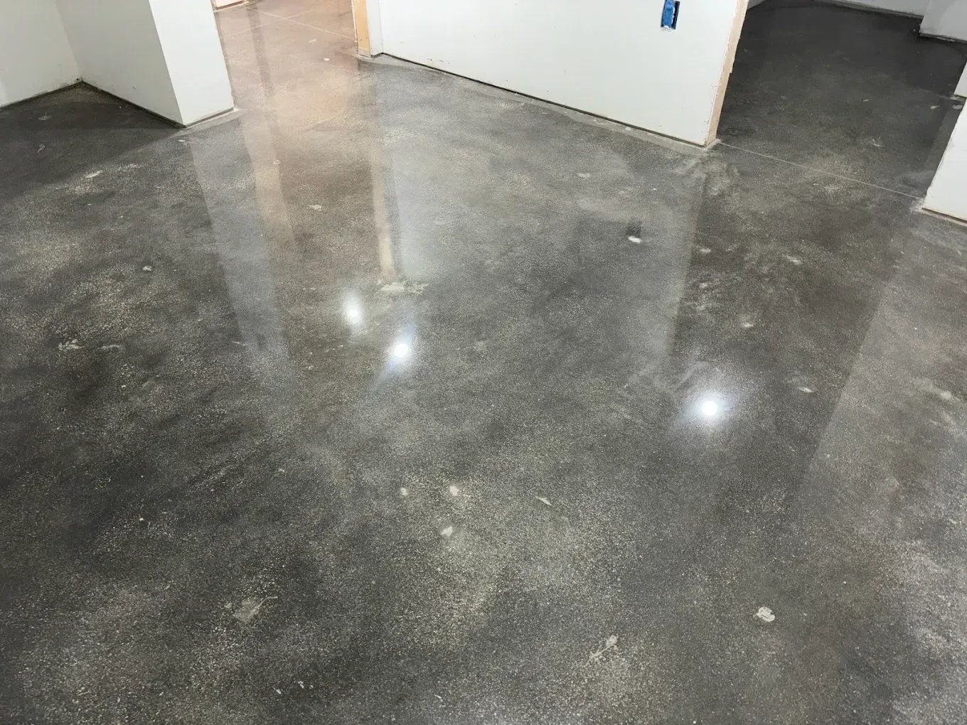 Polished gray concrete floor in an empty room with white walls and doorways