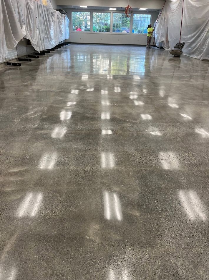 Polished school hallway floor reflecting light, with windows at the far end and draped walls on both sides