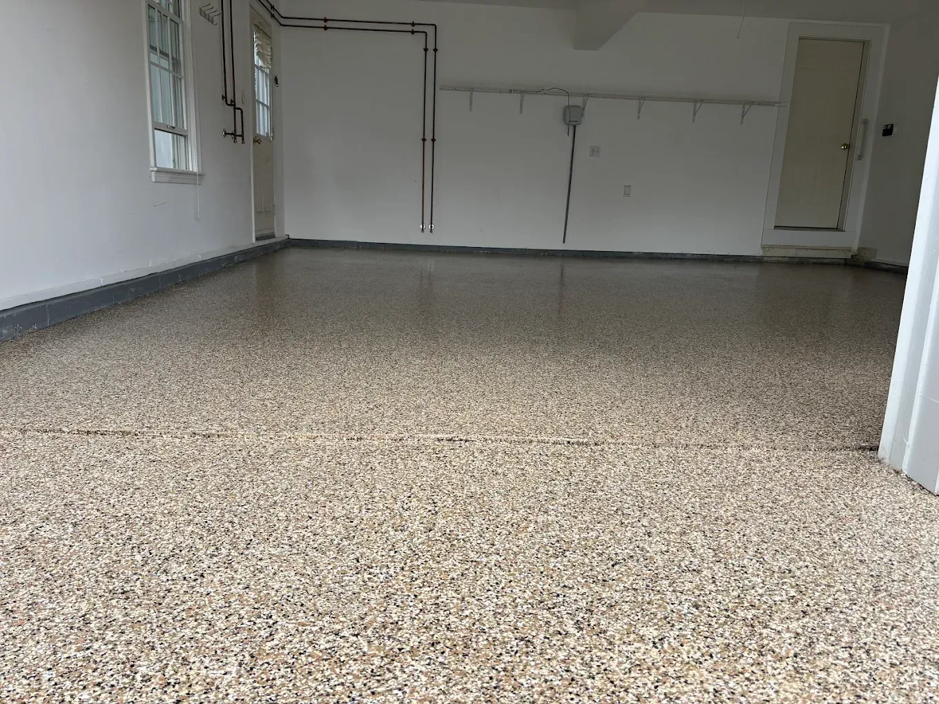 Empty room with speckled floor, white walls, and a closed door