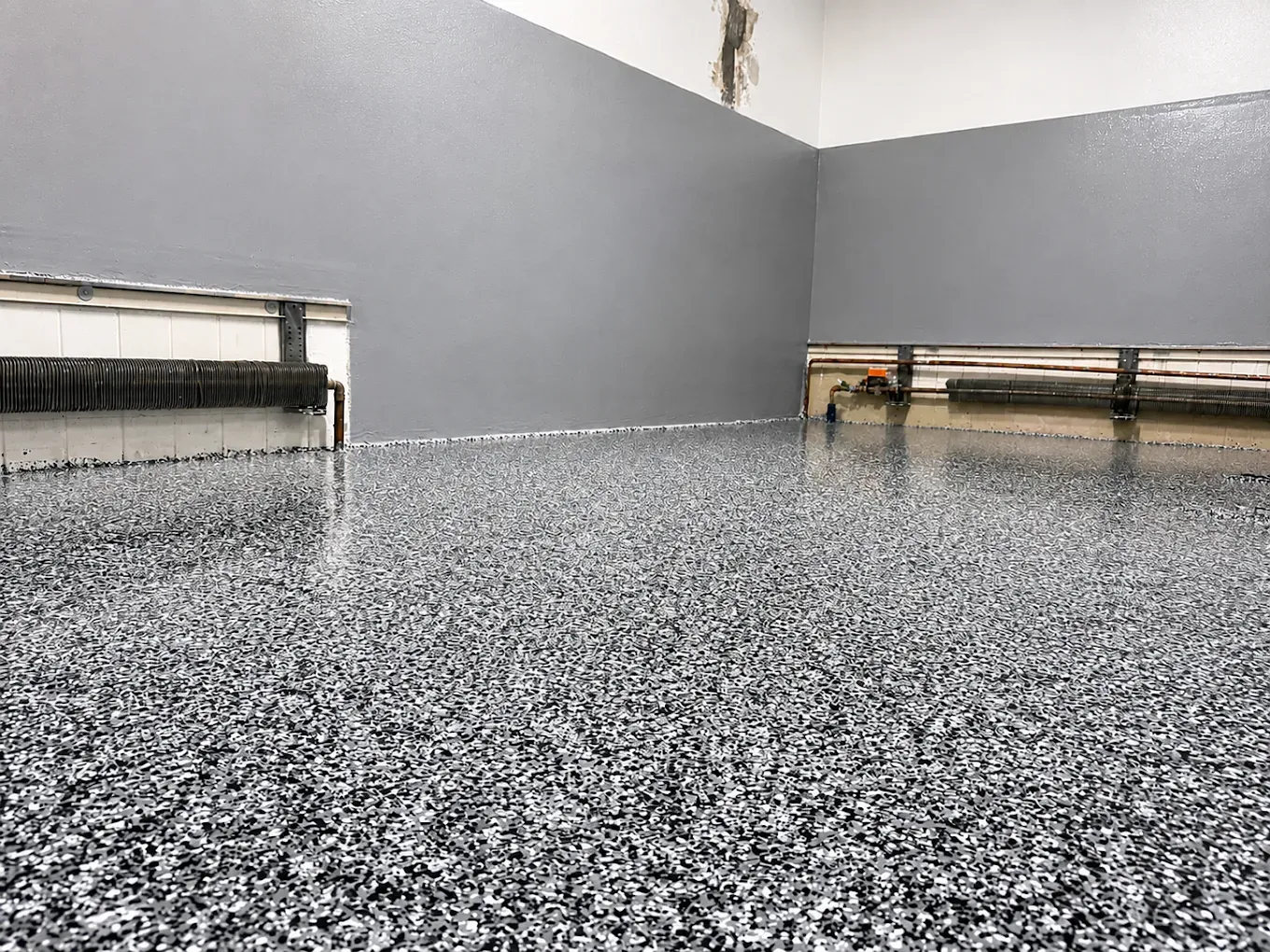 Empty gray room with speckled floor and low benches along the walls