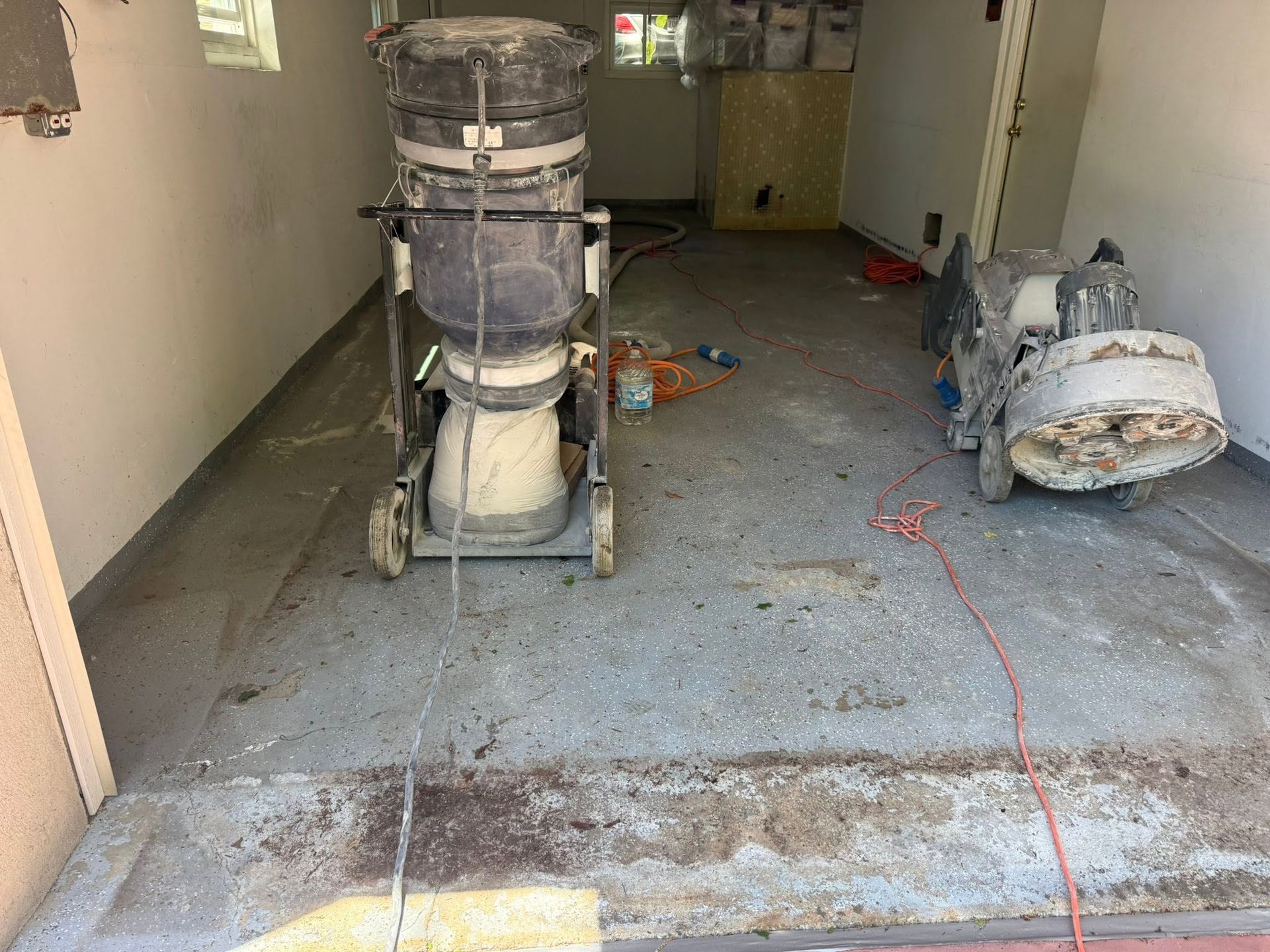 Construction hallway with wet floor, a wet vacuum, tools, and debris on the ground
