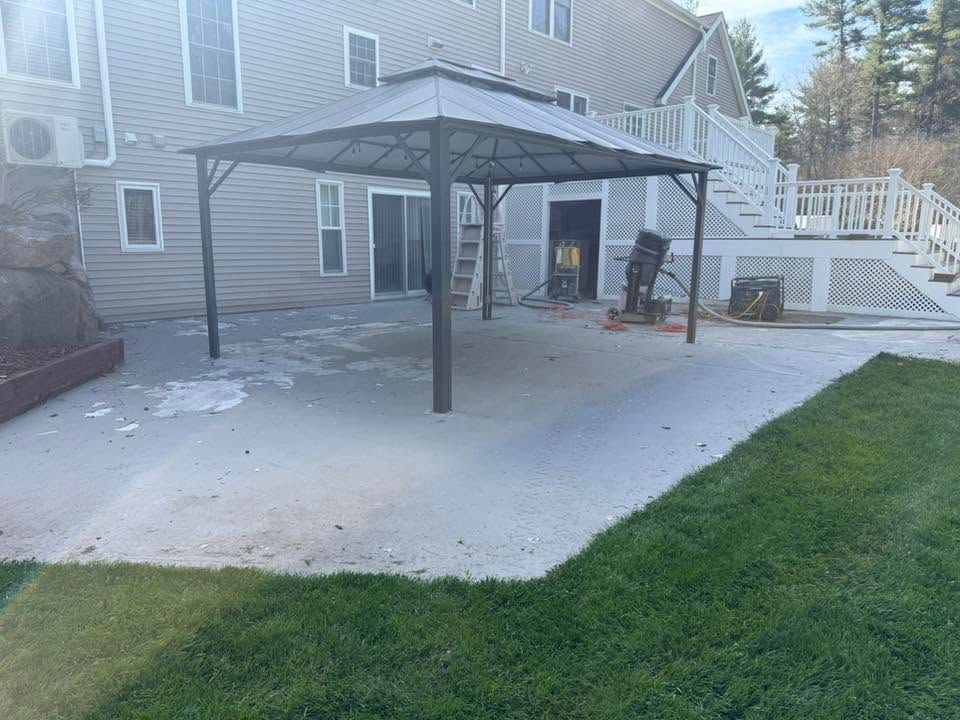 Snow-dusted backyard patio with a black metal gazebo beside a gray house and white staircase