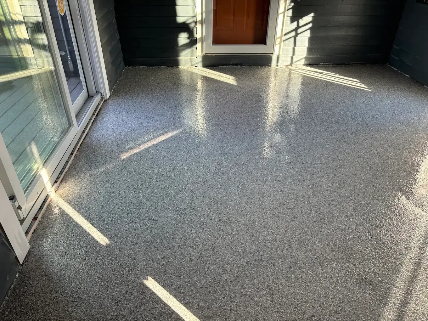 Empty sunlit hallway with speckled gray floor and white doors
