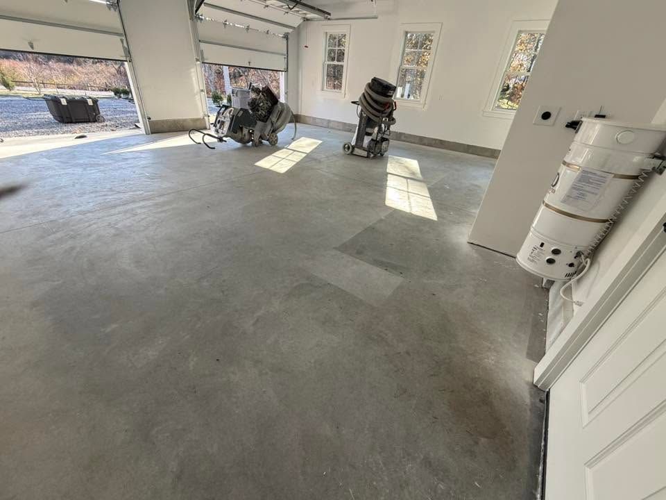 Empty garage with concrete floor, open doors, and a few items stored along the walls.