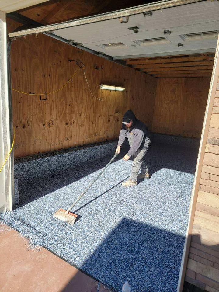 Person raking blue gravel in a wooden garage or shed interior