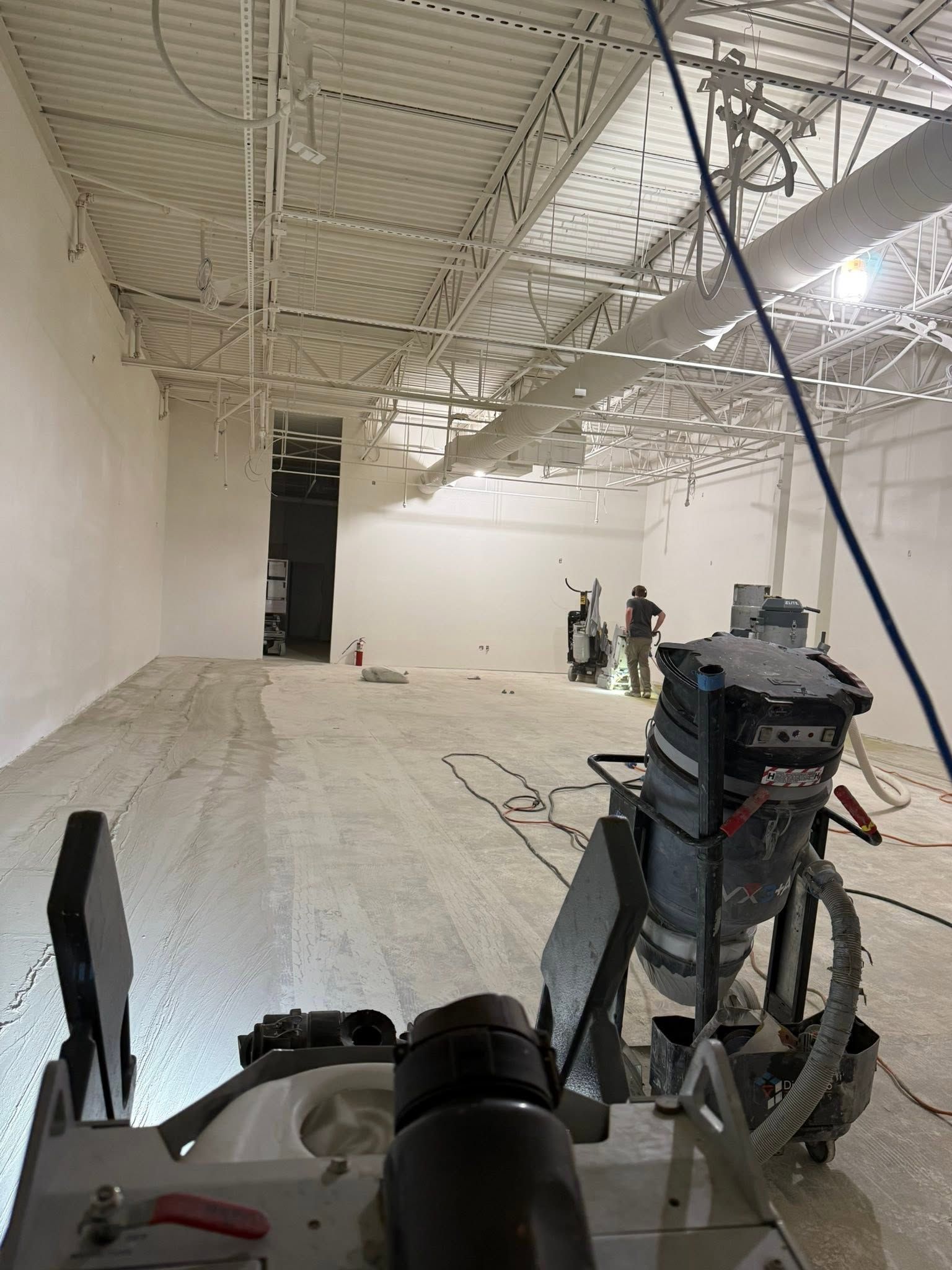 Empty white industrial room with exposed ceiling and equipment carts under construction